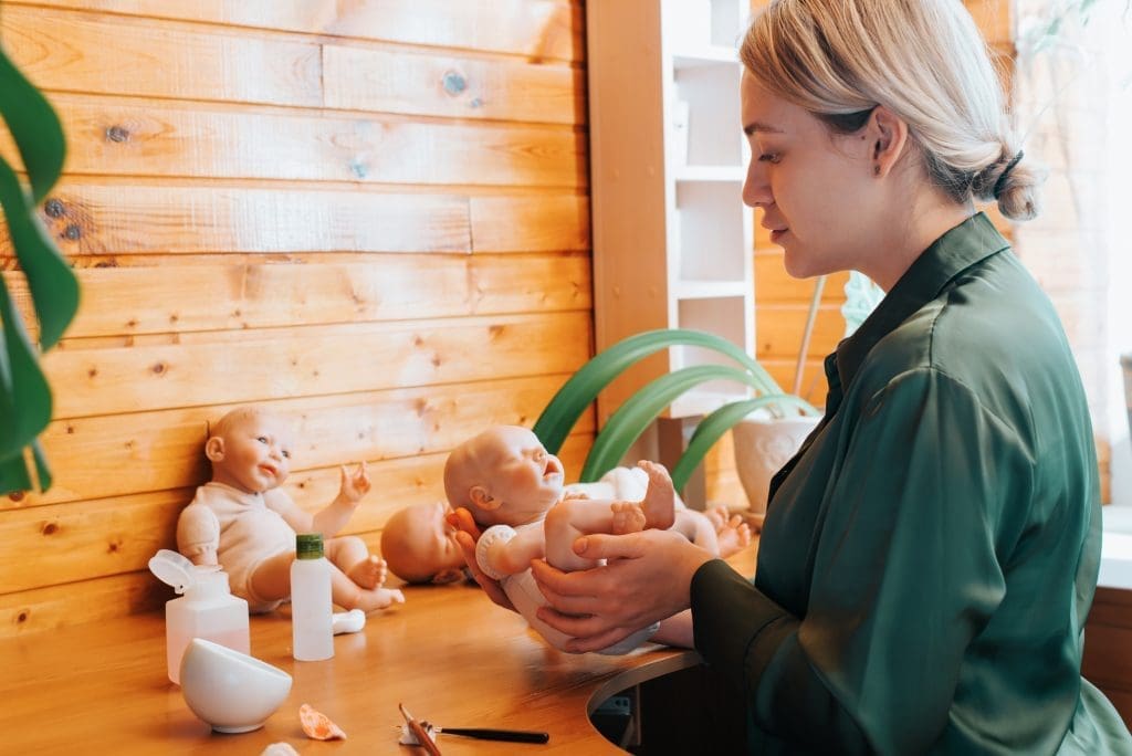 Reborning, hobby, craft, reborning concept. Side view of young female reborn maker holding realistic